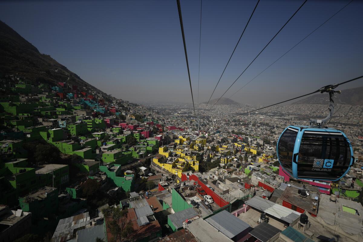 Aerial view of blue sky tram hanging from cables stretched over a dense, colorful neighborhood