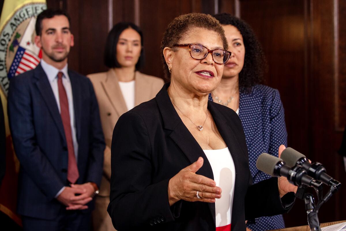 Mayor Karen Bass speaks at a lectern, with staff members behind her