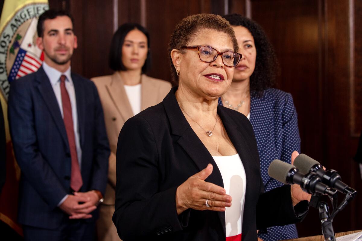 Mayor Karen Bass speaks at a lectern as staff members stand behind her 