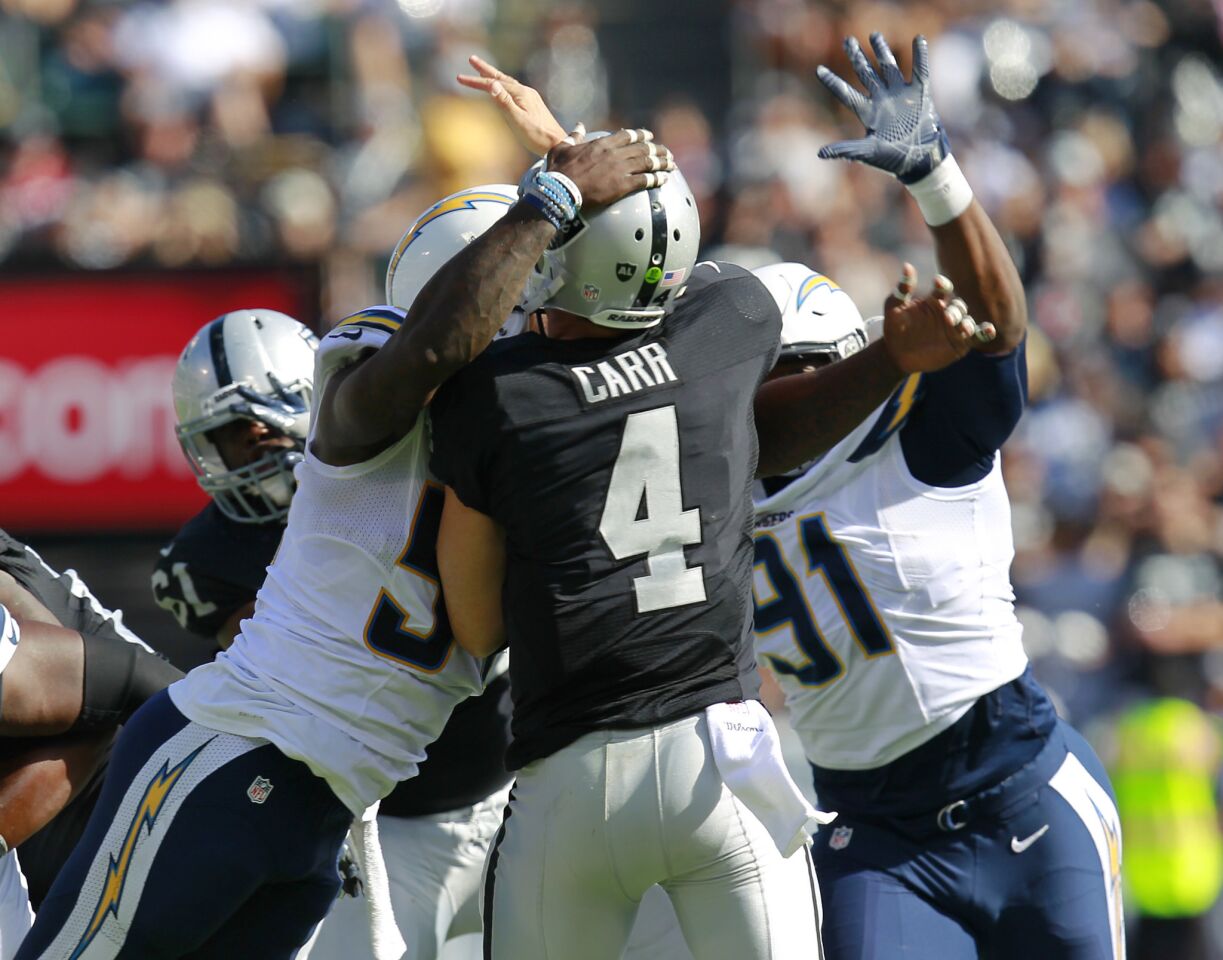 San Diego Chargers Melvin Ingram, left, and Caraun Reid hit Raiders Derek Carr as he throws a touchdown pass to Amari Cooper in the 3rd quarter in Oakland on Oct. 9, 2016. (Photo by K.C. Alfred/The San Diego Union-Tribune)