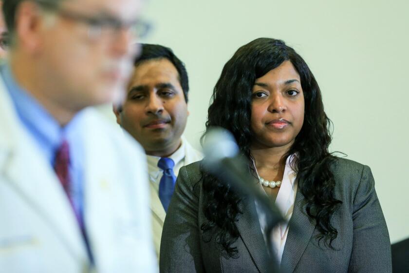 Amber Vinson, a Texas nurse who contracted Ebola after treating an infected patient, listens as Dr. Bruce Ribner, an epidemiologist, speaks to the media during a press conference about Vinson's release from care at Emory University Hospital. Vinson spoke out in several interviews on Thursday.