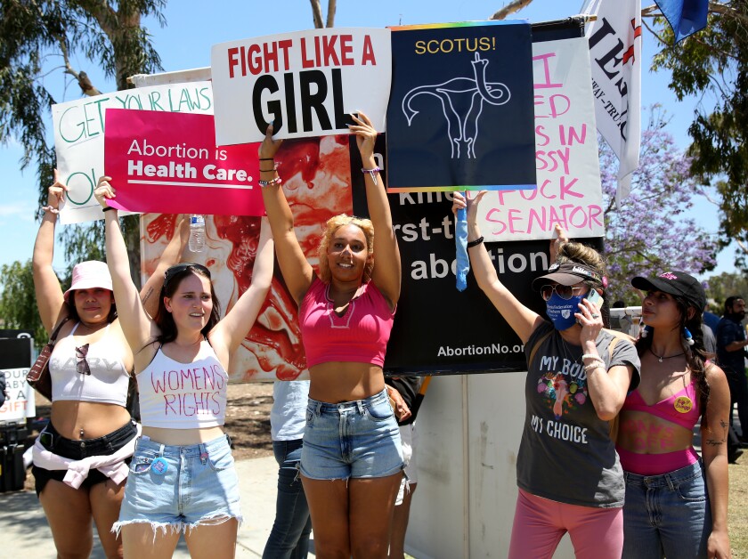 Demonstrators block anti-abortion signs at a "Bans Off Abortion" rally Saturday at Centennial Regional Park in Santa Ana.