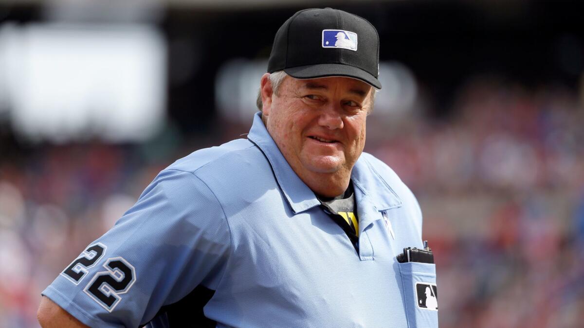 Crew chief Joe West smiles as he talks to staff in the Seattle Mariners dugout during a game against the Texas Rangers on June 17.