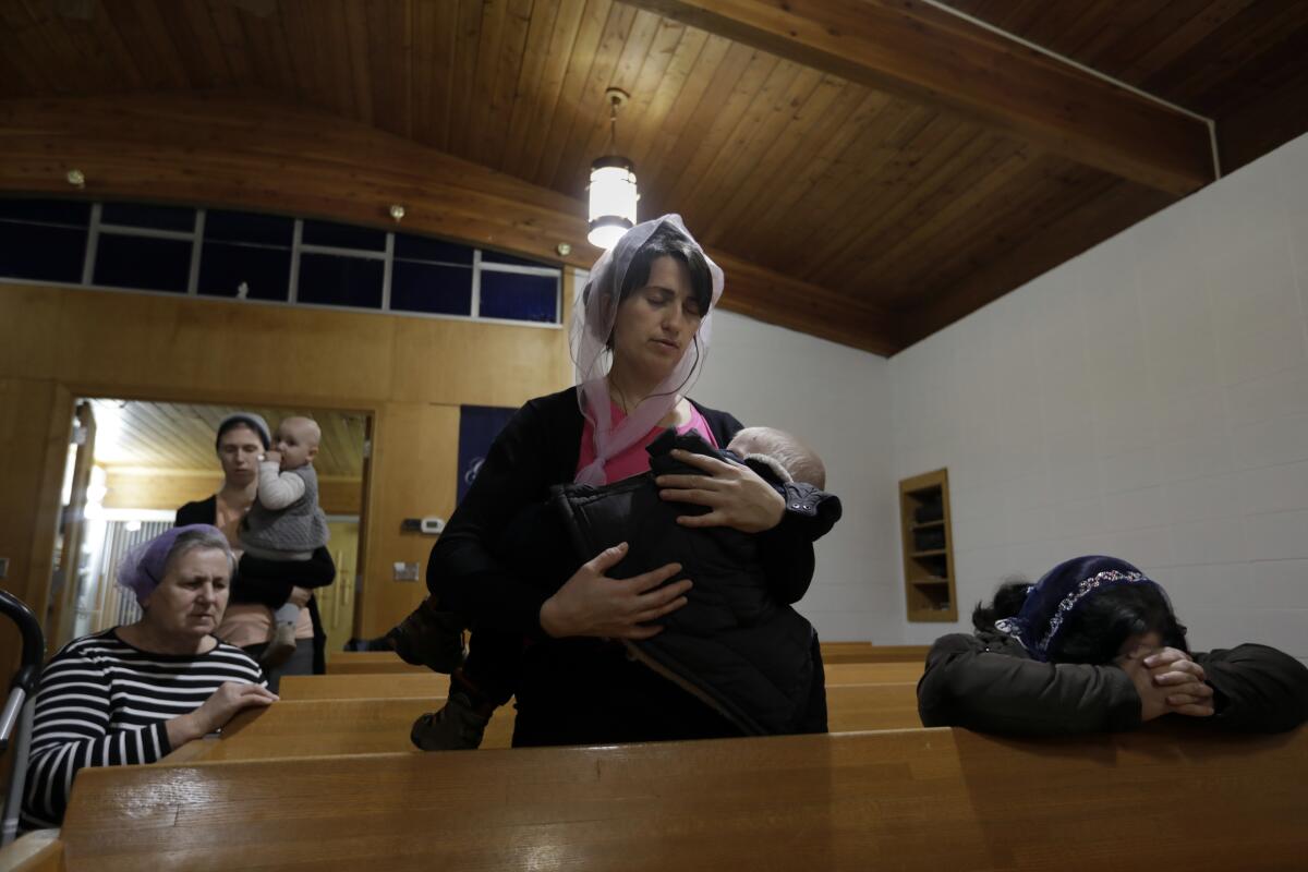 Yuliia Kulybchuk, de 33 años, sostiene a su hijo Tymofii, de 20 meses, durante el culto de la Iglesia Luterana Libre del Calvario en Bismarck.