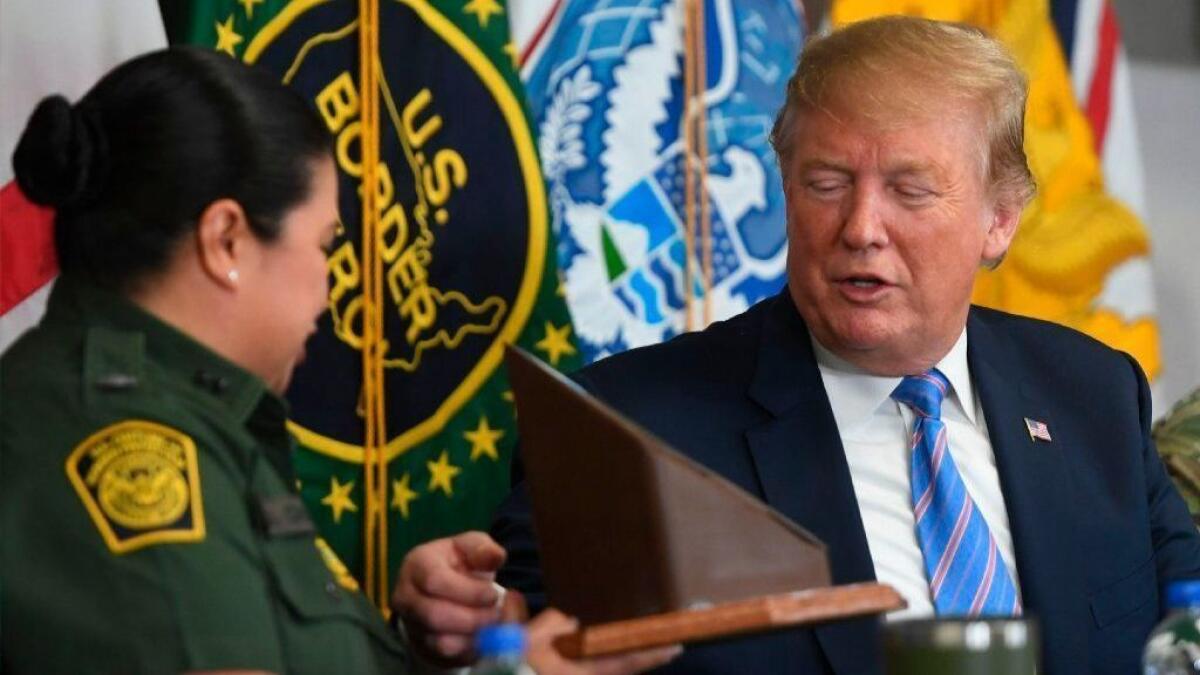 President Trump is presented with a souvenir piece of border barrier by Border Patrol agent Gloria Chavez during a discussion of immigration and border security April 5 in Calexico.