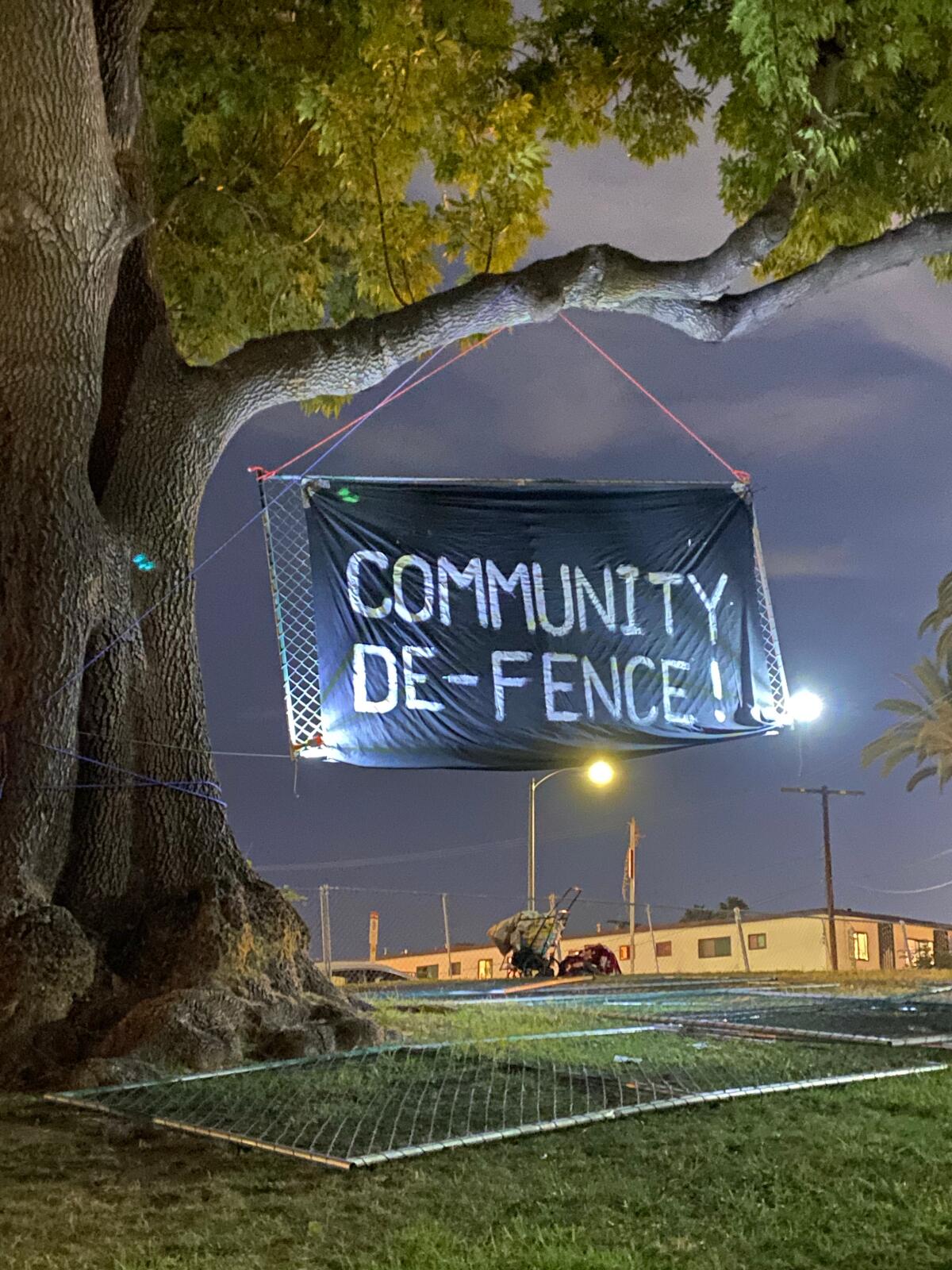 A sign is hung by fencing that was torn down around Echo Park Lake Sunday night.