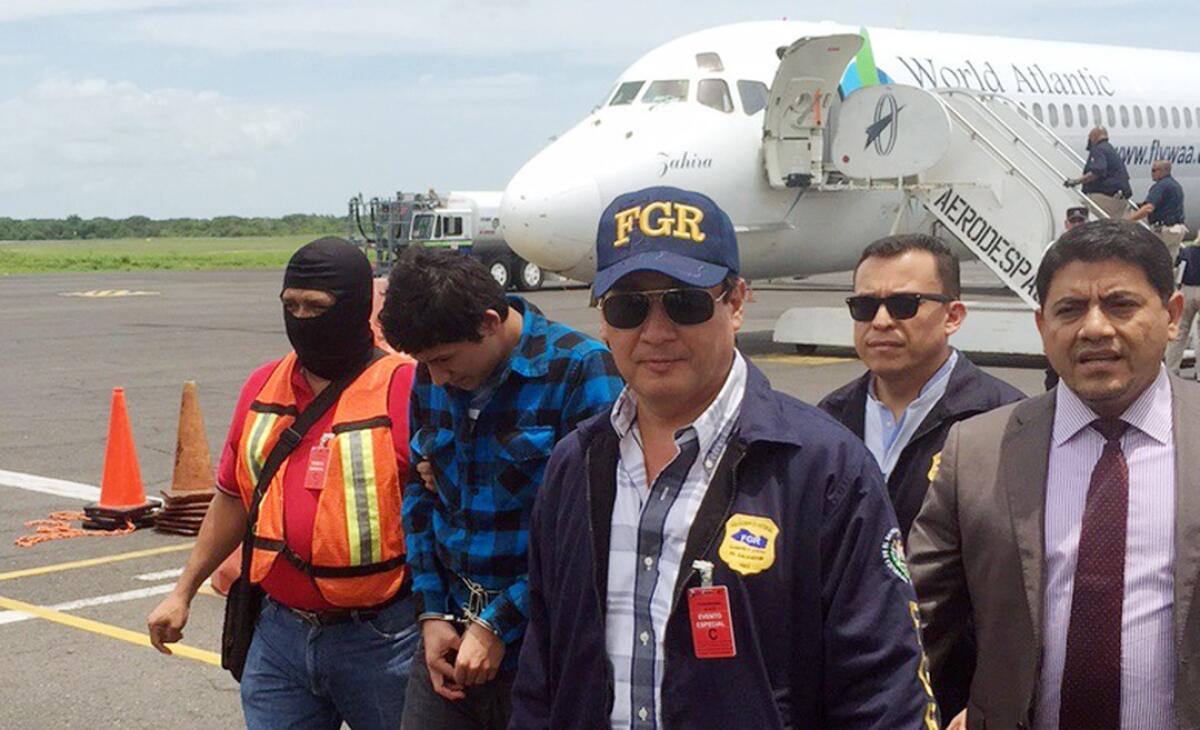 El fiscal general de El Salvador, Luis MartÌnez, con gorra azul, escolta a Javier Arnoldo CerÛn GÛmez, segundo desde la izquierda, en la pista del aeropuerto en San Salvador, el viernes 4 de septiembre de 2015. CerÛn fue entregado por Estados Unidos a las autoridades salvadoreÒas que lo buscaban por el asesinato a tiros del fiscal AndrÈs Ernesto Oliva Tejada, ocurrido en marzo. Las autoridades estadounidenses decidieron deportar a CerÛn desde Arizona para evitar extraditarlo. (VÌa AP Foto/Servicio de Control de InmigraciÛn y Aduanas).