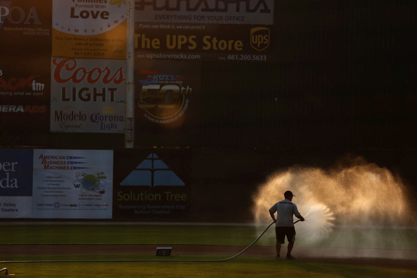A groundskeeper waters down the field in the late afternoon light before the Blaze play one of their last games at Sam Lynn Ballpark.
