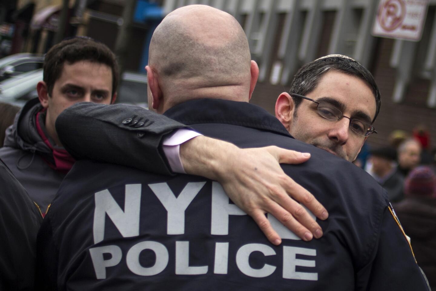 A man, who gathered with dozens to show support for policemen two days after officers Wenjian Liu and Rafael Ramos were shot and killed as they sat in a marked squad car in Brooklyn on Saturday, embraces a New York Police Department (NYPD) officer