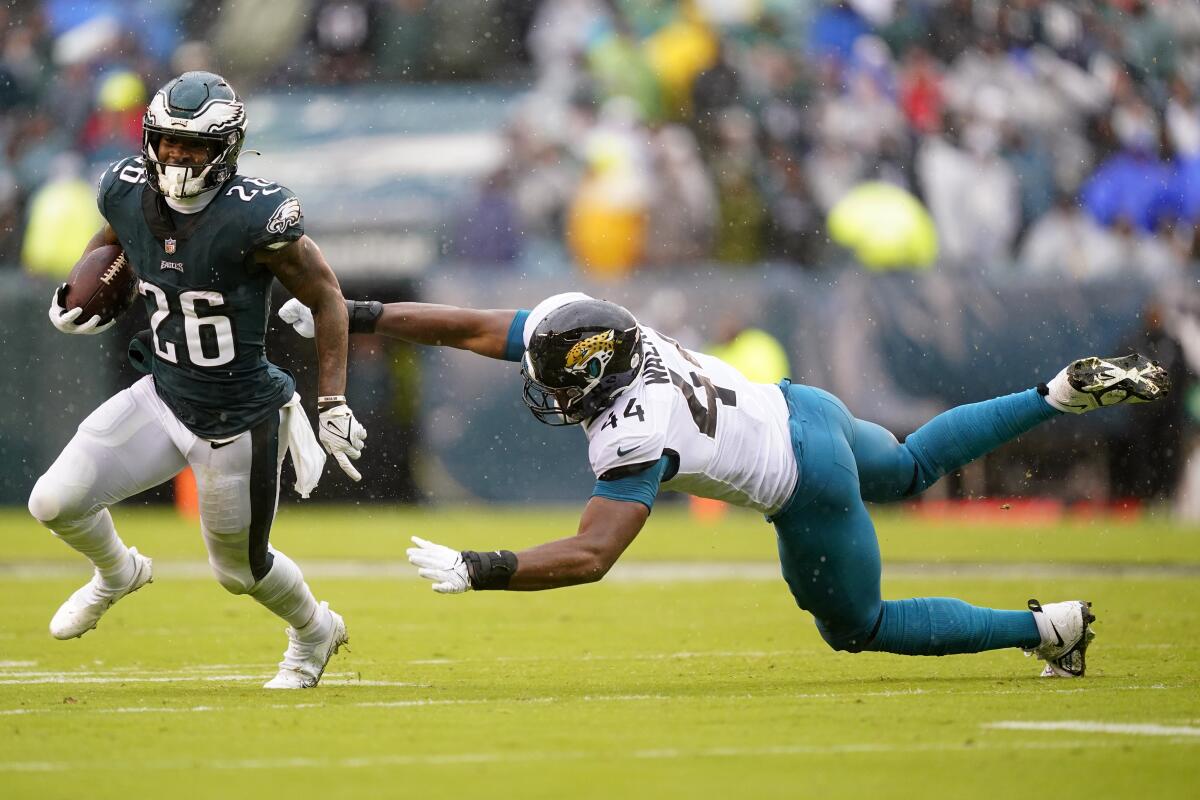 Philadelphia Eagles running back Miles Sanders runs with the ball past Jacksonville Jaguars linebacker Travon Walker.