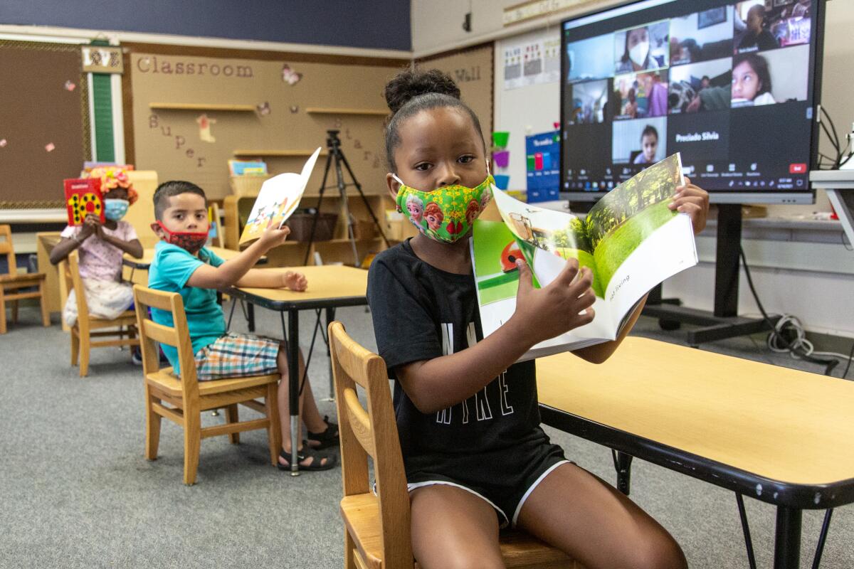 Malika Odom, Jeremiah Enriques, and Ryleigh Staton show their transitional kindergarten books at Valencia Park Elementary.