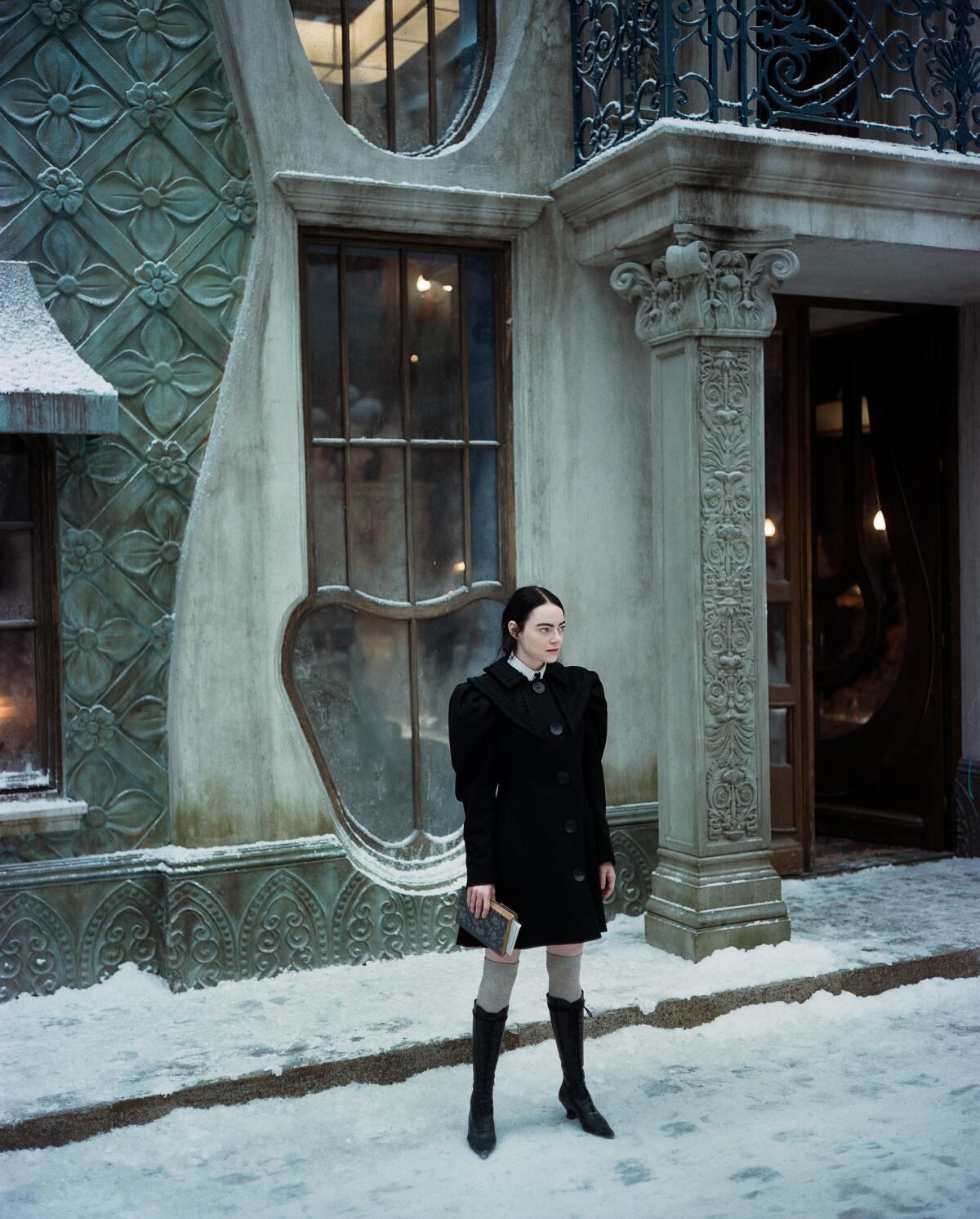 Emma Stone stands in the snow wearing a matching black skirt and jacket near the film's end.