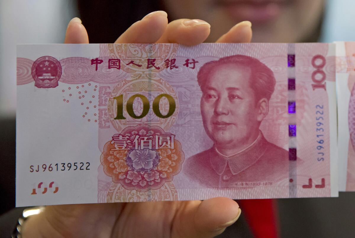 FILE - In this Nov. 12, 2015, file photo, staff member displays an 100-yuan RMB banknote at the Bank of China Tower in Hong Kong. China’s central bank is trying to restrain the surging exchange rate of its currency, temporarily backtracking in efforts to make the tightly controlled yuan more flexible and market-oriented. (AP Photo/Kin Cheung, File)