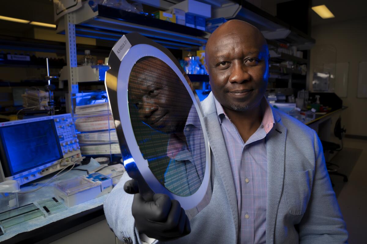 Founder and CEO of Roswell Biotechnologies in Sorrento Valley, Paul Mola holds up a large silicon chip wafer.