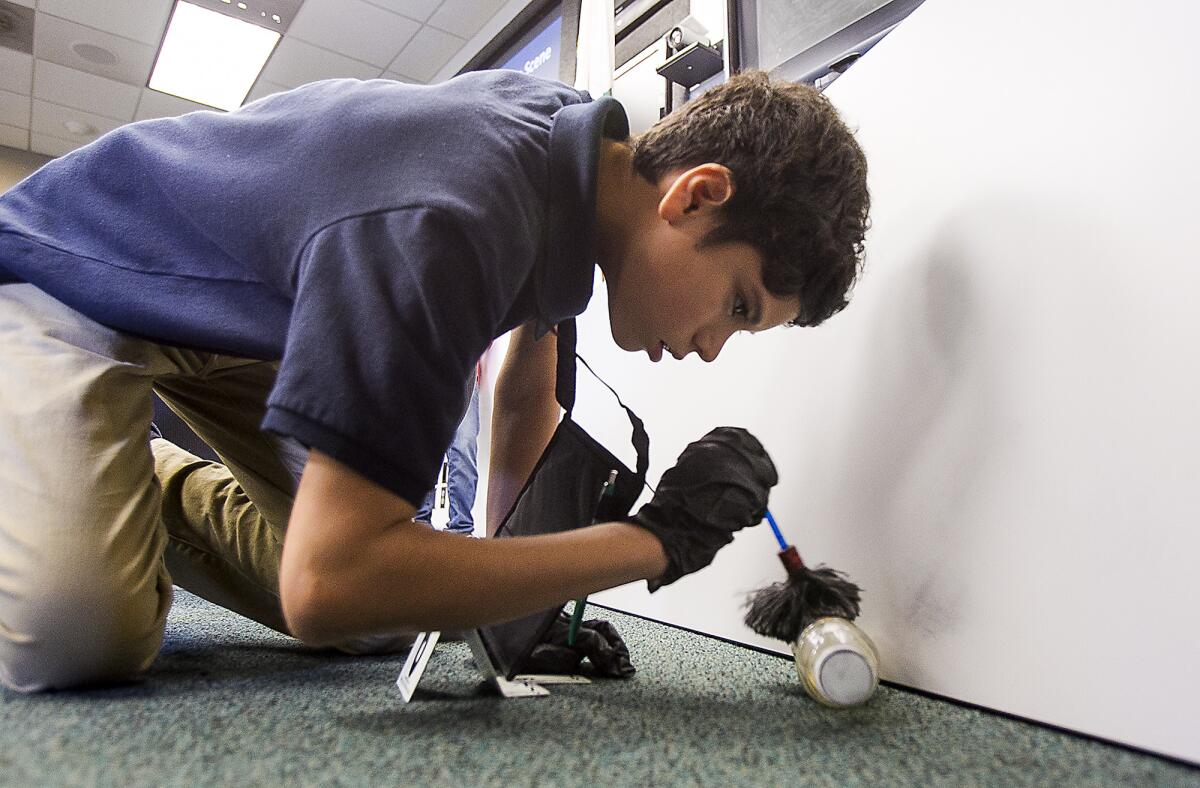 Mateo Sanchez dusts a piece of evidence for fingerprints during a mock crime scene using CSI techniques during the Teen Community Police Academy put on by Irvine Police on Tuesday, August 11.