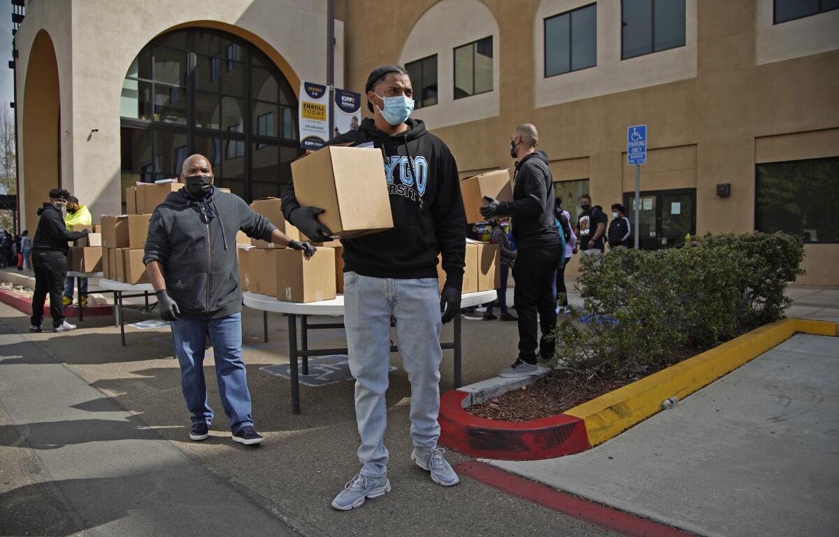 Ryan Anthony holds a box of food while volunteering at a food and laptop drive at Jacob Center Saturday.