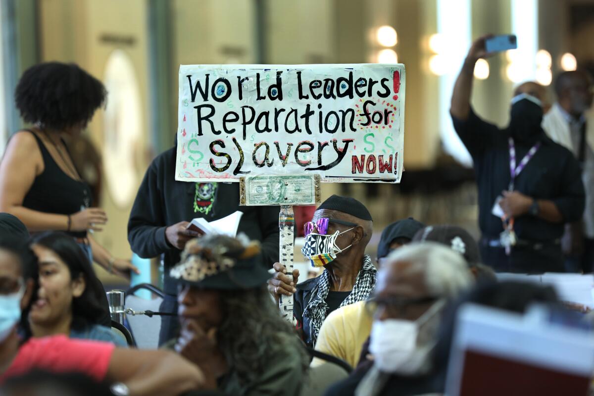 A member of the audience holds up a sign as the California Reparations Task Force meets in Los Angeles on Sept. 23, 2022.