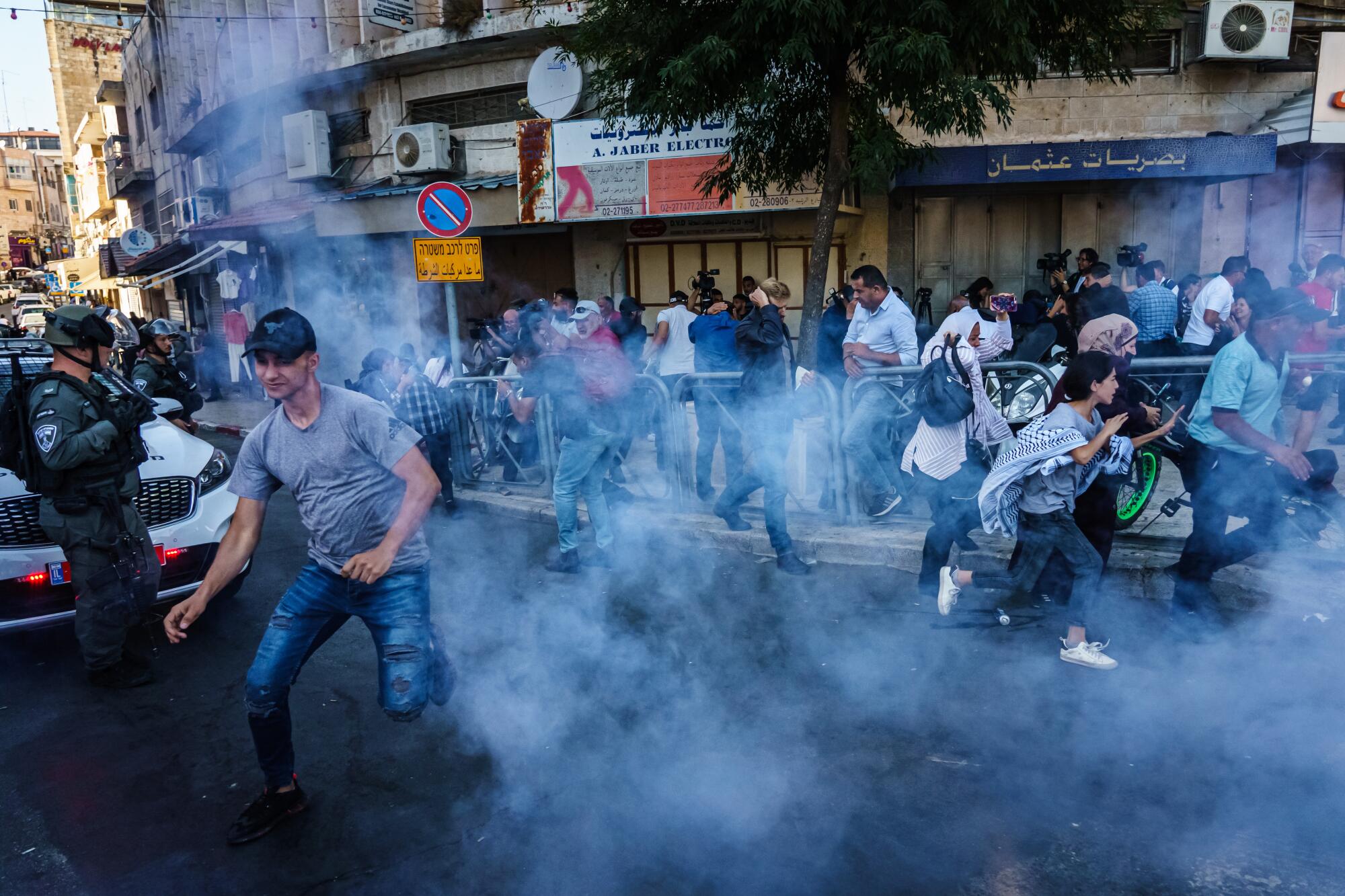 Israeli security forces throw stun grenades to disperse a crowd gathered for a news conference.