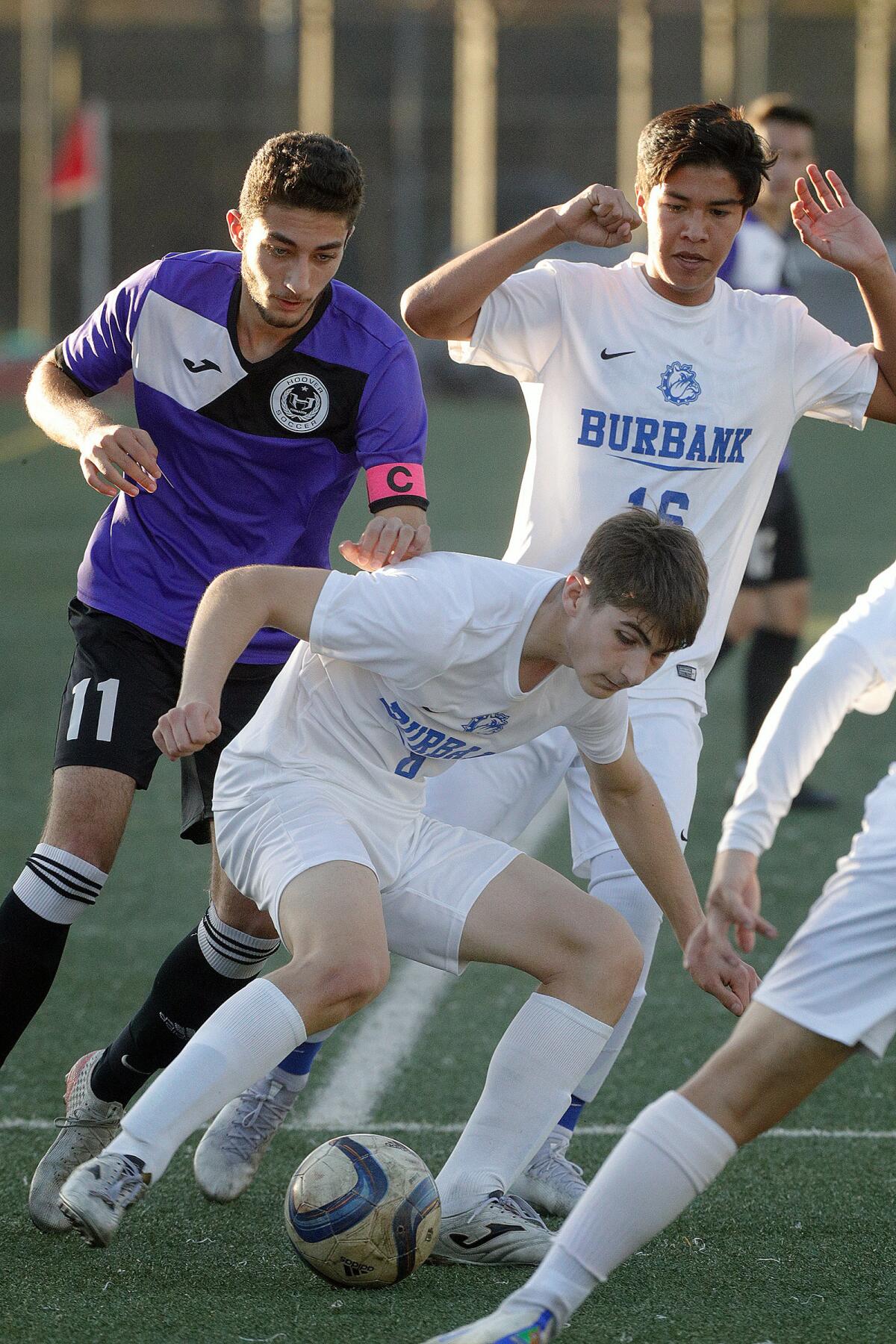 Burbank’s Garik Kirahosyan (in front) seemingly sneaks in from the side to take the ball off the foot of Hoover’s Kevin Mirzakhanian who was being pursued by Burbank’s Freddy Cardenas in a Pacific League boys' soccer game at Hoover High School on Friday, January 3, 2020.