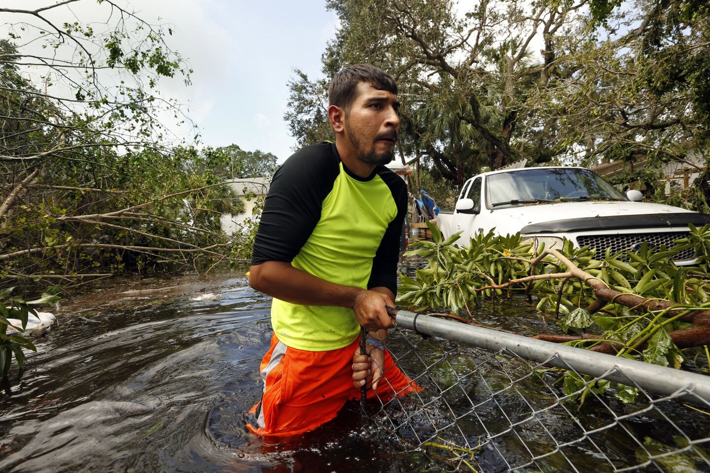 Israel Alvarado, 25, tries to open a gate blocked by fallen tree branches to retrieve a generator in Bonita Springs.
