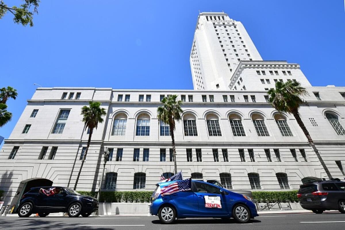 Cars drive past Los Angeles City Hall.