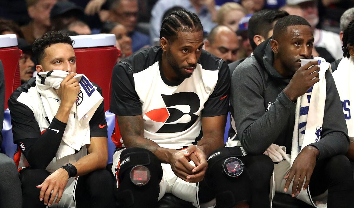 Clippers star Kawhi Leonard, center, sits on the bench during the first half against the Portland Trail Blazers.