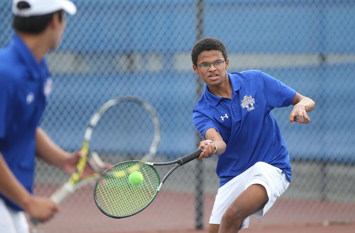 Fountain Valley's Malik Thiaw, right, catches up to a volley as doubles partner Albert Ly watches in a nonleague match against Beckman on Thursday.
