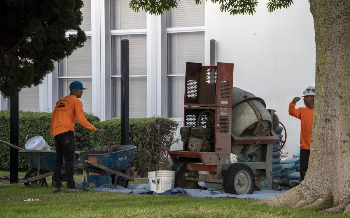 Construction workers mix concrete for a new fence around Fremont Elementary School