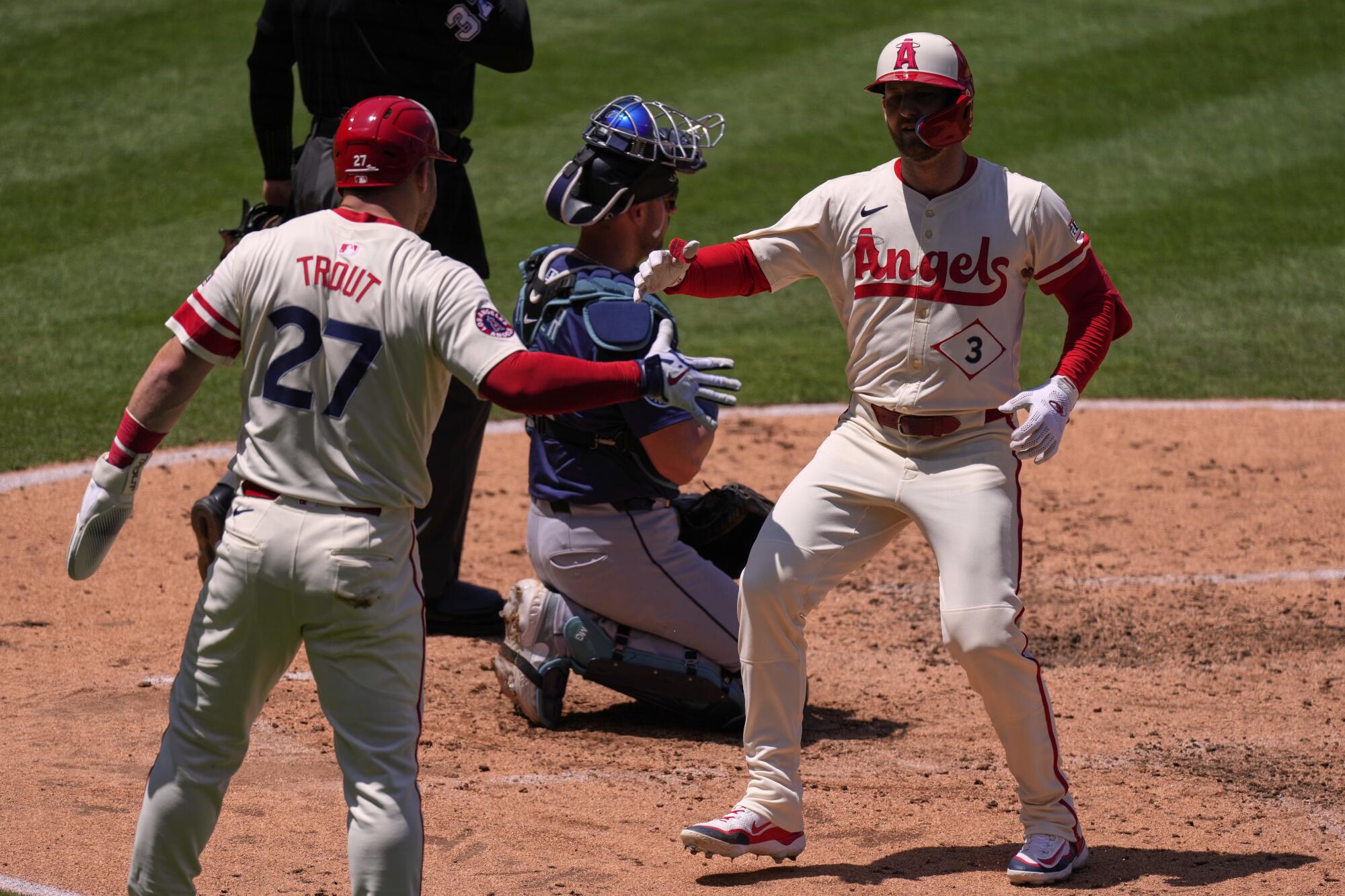 Taylor Ward, a la derecha, es felicitada por Mike Trout, a la izquierda, después de golpear un jonrón de dos carreras.