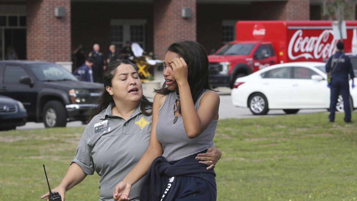 A student is comforted by a Forest High School official after a shooting at the campus in Ocala, Fla., on Friday, April 20, 2018.