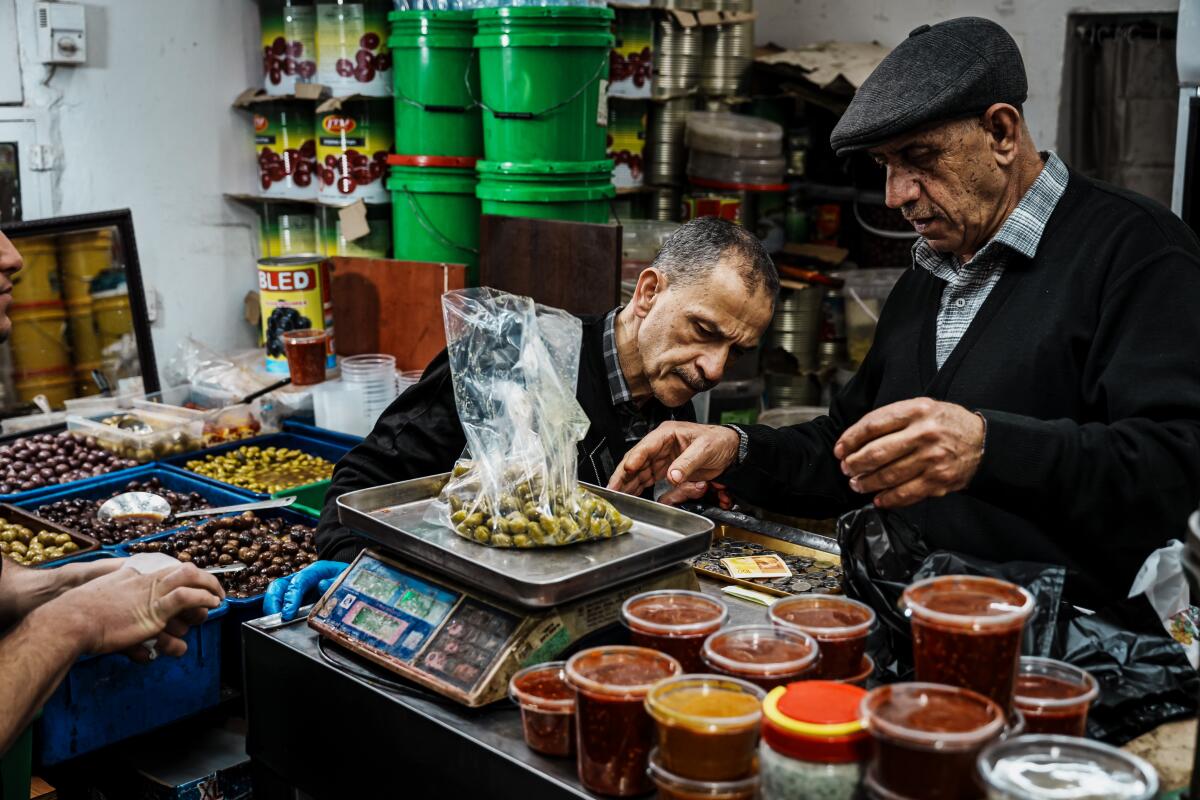 Abu Ali Eid weighs a bag of pickled olives for customers.