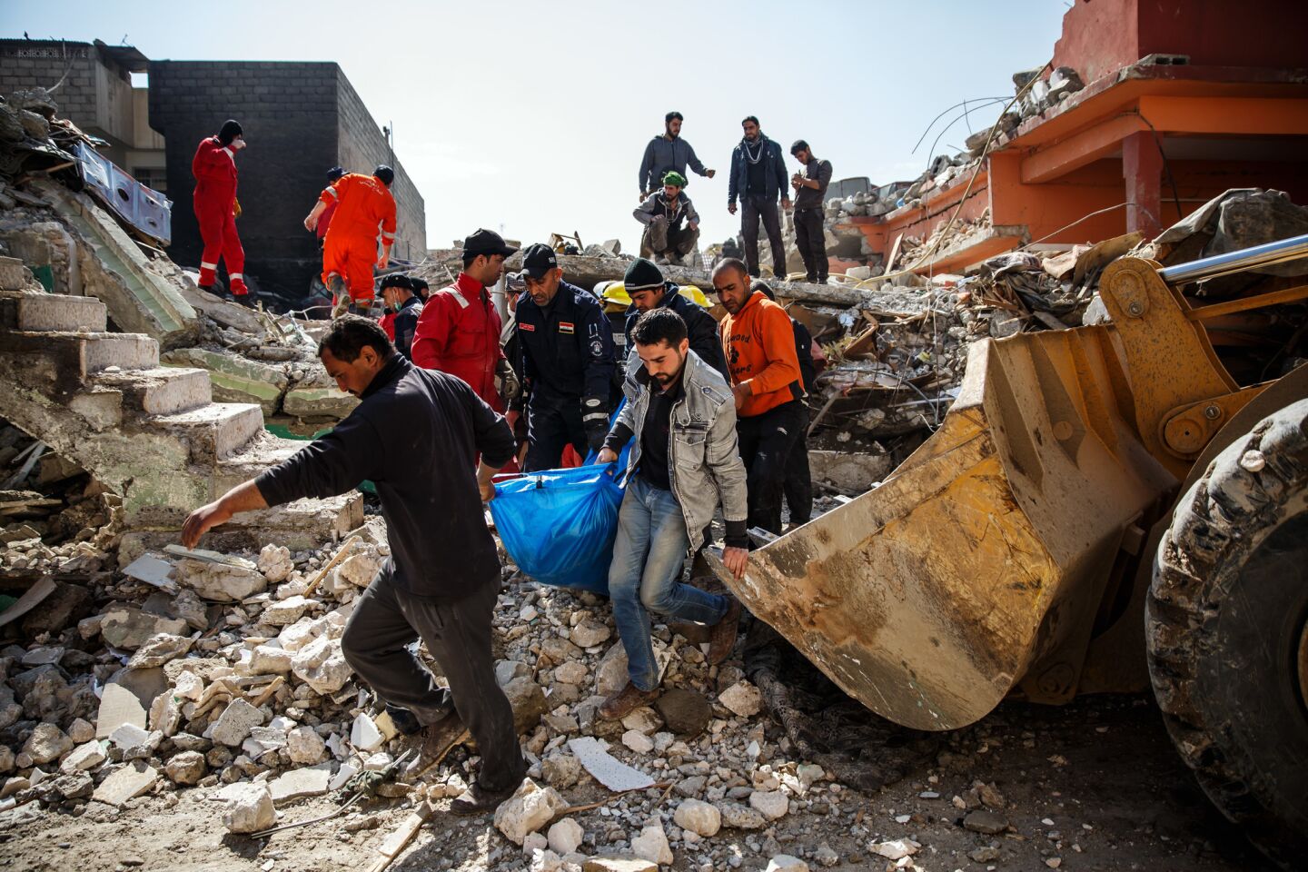 With the help of family members, Iraqi Civil Defense members recover a body that was buried in the rubble of a home destroyed by an airstrike in Mosul, Iraq.