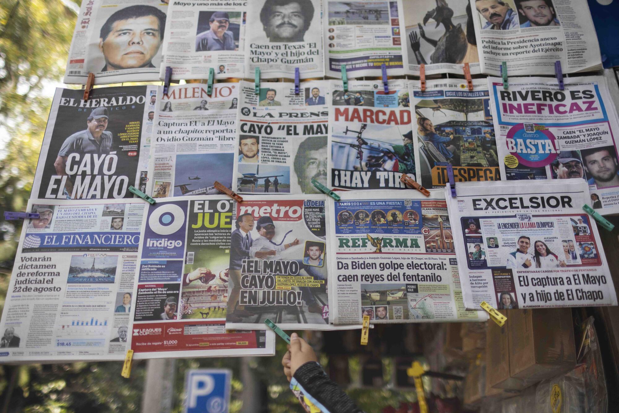 A collection of Mexican newspapers' front pages held together by clothespins