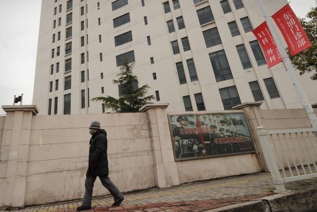 A person walks past a 12-story building in a Shanghai suburb alleged in a February report by the U.S. Internet security firm Mandiant Corp. to be the home of a Chinese military-led cyber-espionage group.