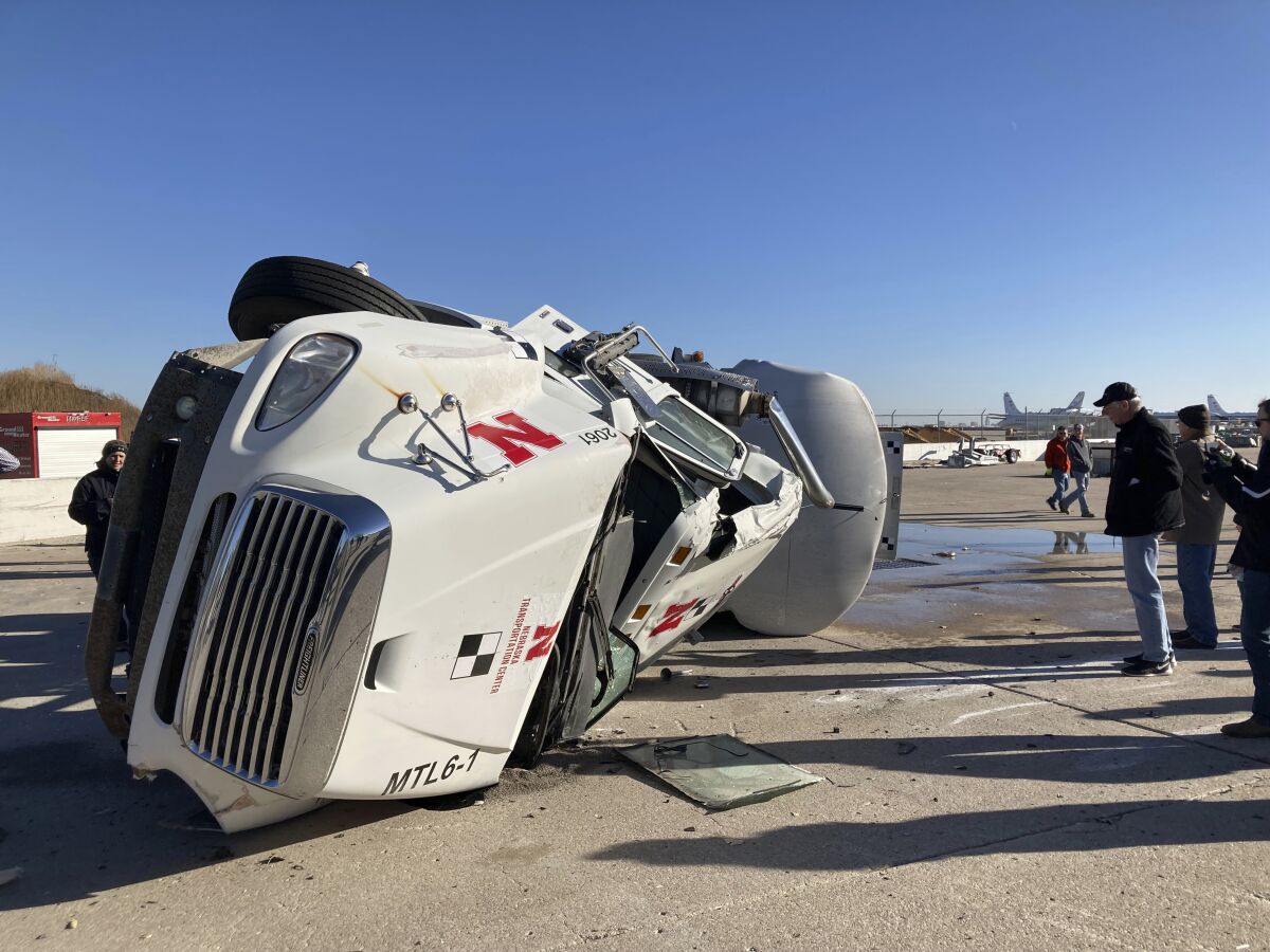 A 2010 Freightliner Columbia lies on its side after crashing into a concrete barrier at a University of Nebraska-Lincoln test facility on Wednesday, Dec. 8, 2021, in Lincoln, Neb. University researchers conducted the experiment with a loaded, 80,000-pound tractor-tanker to test the effectiveness of a new concrete barrier that was designed to reduce the severity of such extreme crashes. The research has piqued the interest of many U.S. states and other countries. (AP Photo/Grant Schulte)