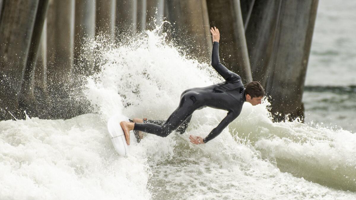 A surfer rides a wave on the north side of the Huntington Beach Pier on Tuesday. A storm in the South Pacific is expected to send 4- to 6-foot waves or higher to south-facing Orange County beaches through Thursday.