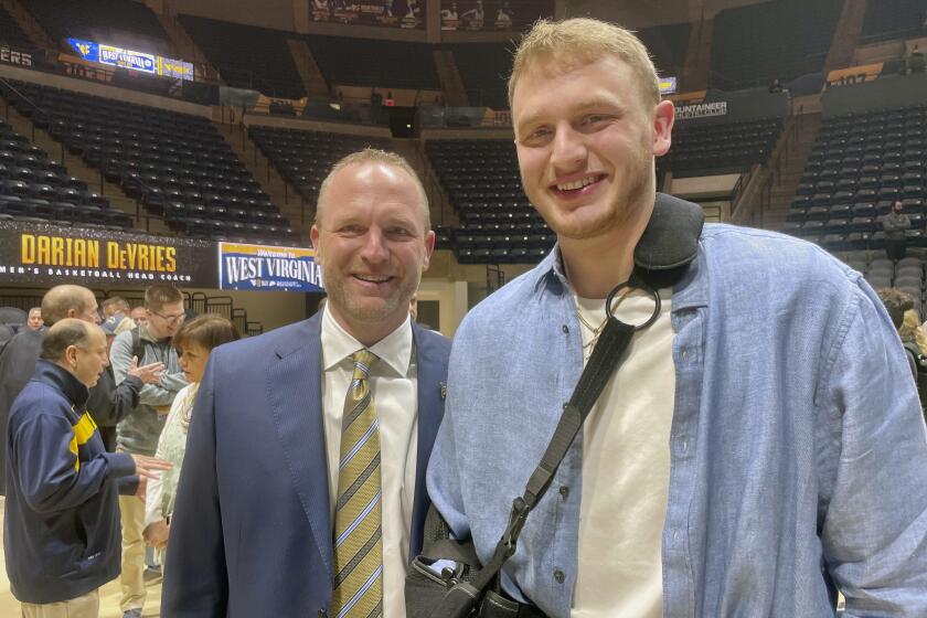 New West Virginia men's NCAA college basketball coach Darian DeVries poses with his son, Tucker, after an introductory news conference Thursday, March 28, 2024, in Morgantown, W.Va. Tucker DeVries announced that he will transfer from Drake to continue playing for his father. (AP Photo/John Raby)