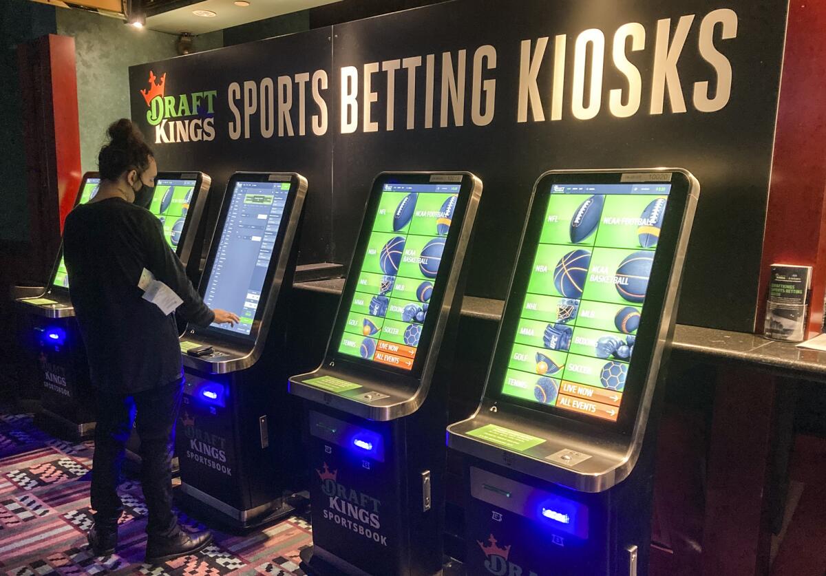 A person stands near sports wagering kiosks.