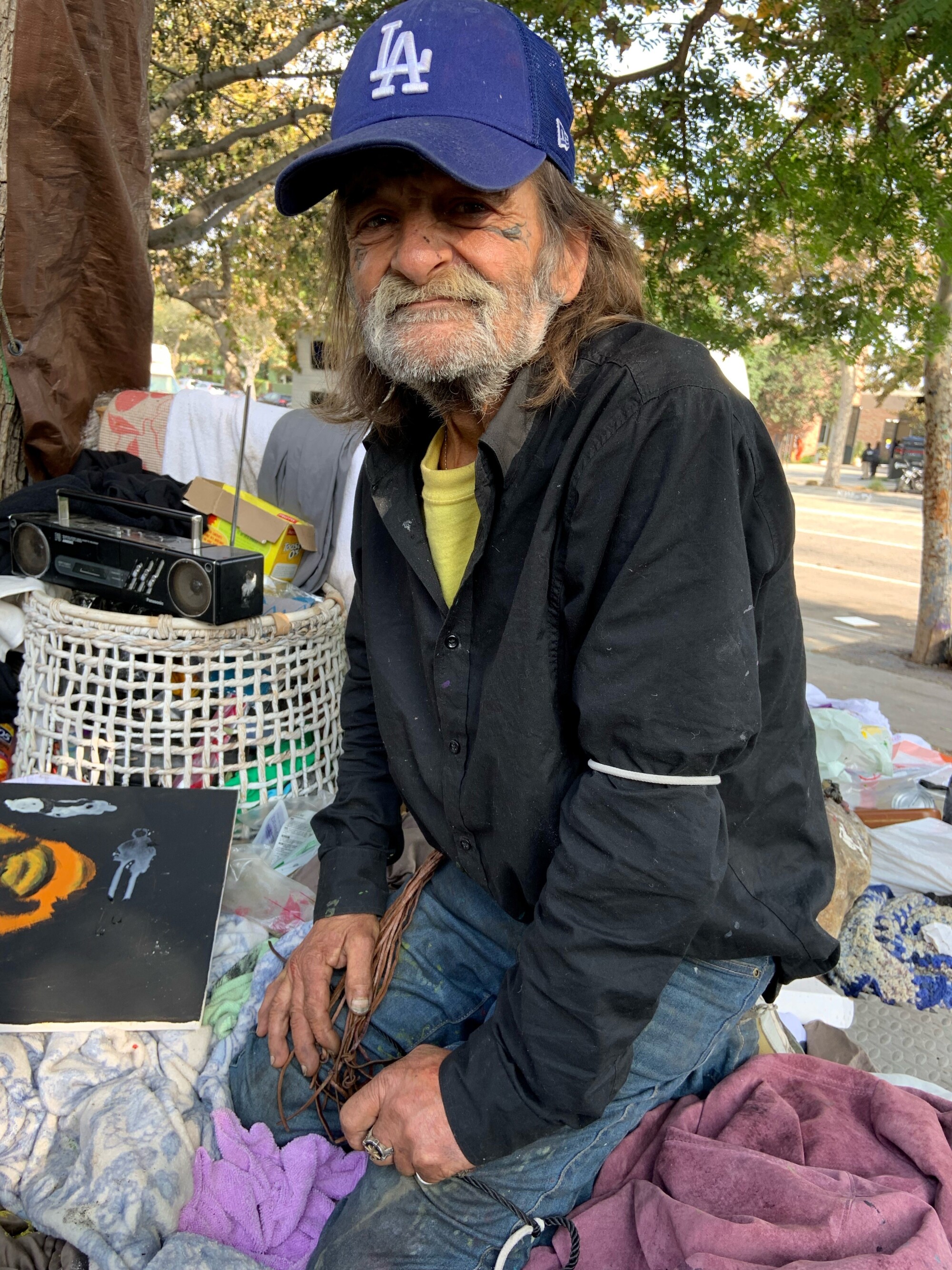 A man in a Dodgers hat on some blankets