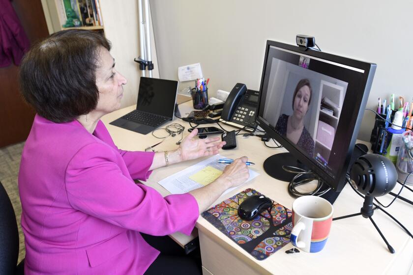 Psychologist Mary Alvord, left, holds an online video conference with a colleague instead of meeting in person.