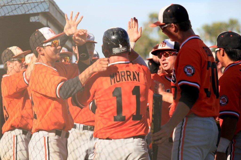 Huntington Beach High's Tyler Murray (11) is congratulated by teammates after hitting a solo home run during the sixth inning against Newport Harbor in a Sunset League game on Tuesday.