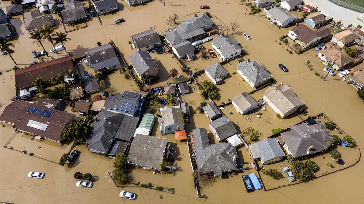 Brown water surrounds houses and vehicles.