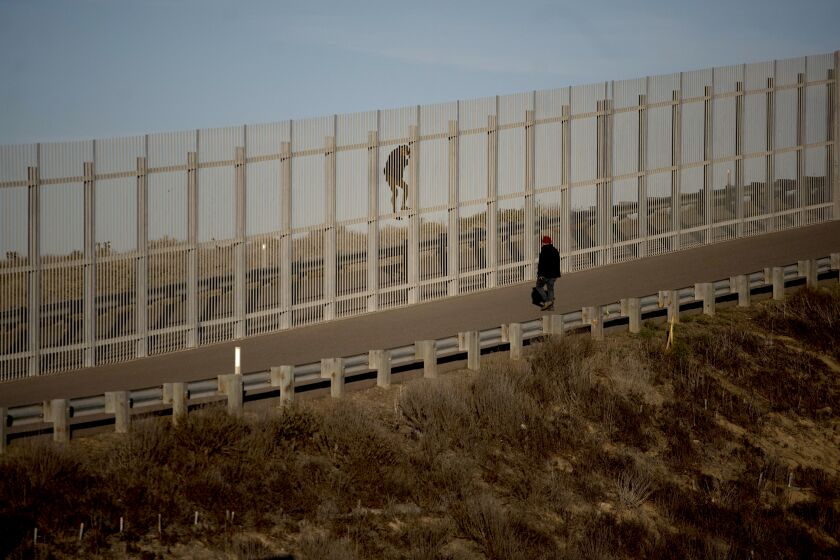 In a photo taken from the Tijuana, Mexico, side of the border, two immigrants on U.S. soil try to jump the second wall before border police arrived and arrested them, Sunday, Dec. 2, 2018. Thousands of migrants who traveled via caravan are seeking asylum in the U.S., but face a decision between waiting months or crossing illegally, because the U.S. government only processes a limited number of cases a day at the San Ysidro border crossing in San Diego. (AP Photo/Ramon Espinosa)