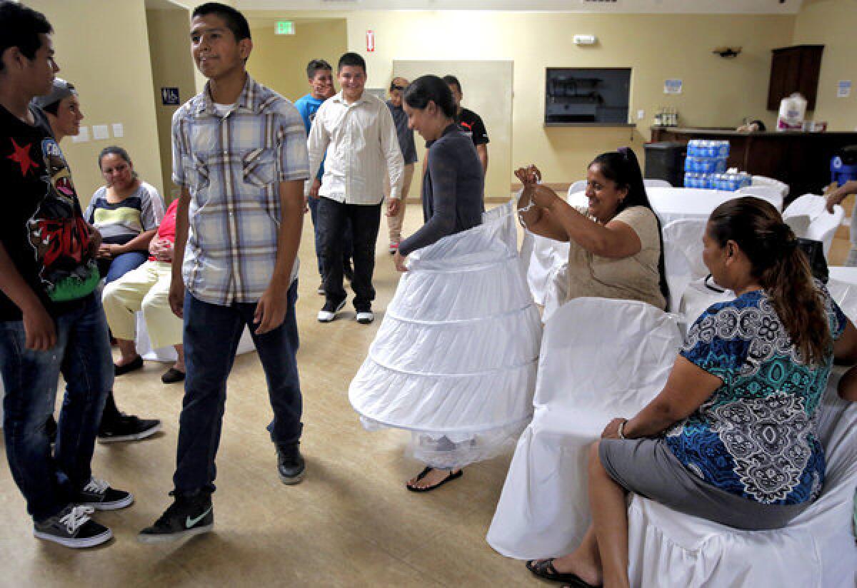 Elvia Renteria, center, has her hoop skirt tie by her mother Milca Urquiza at a dance rehearsal for her upcoming quinceañera in Van Nuys. Elvia is paying for a dance partner, instead of enlisting a friend or cousin. "This is new to me," her mother said. "But things change and, well, nothing¿s free in this world."