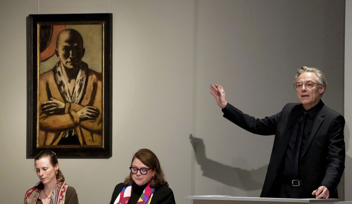 Auctioneer Markus Krause gestures in front of the painting 'Selbstbildnis gelb-rosa' (self-portrait yellow-rose), 1943 oil on canvas, by German painter Max Beckmann, as it is auctioned in Berlin, Germany, Thursday, Dec. 1, 2022. A self-portrait painted during World War II by German expressionist artist Max Beckmann has been sold in Berlin for 20 million euros ($20.7 million), which appears to be a record for an art auction in Germany. (AP Photo/Michael Sohn)