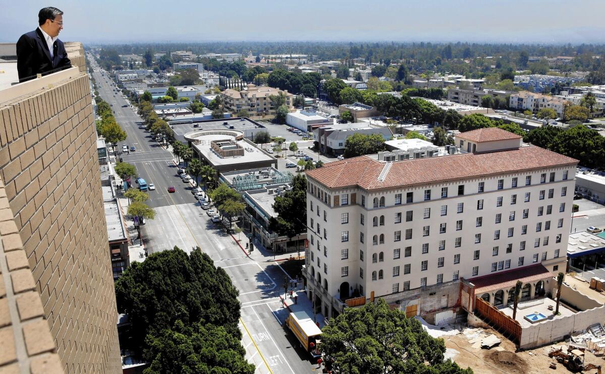 William Chu, left, finance chief of Singpoli, the Hong Kong real estate investment firm that owns the DusitD2 Constance Pasadena, looks toward the hotel, right.