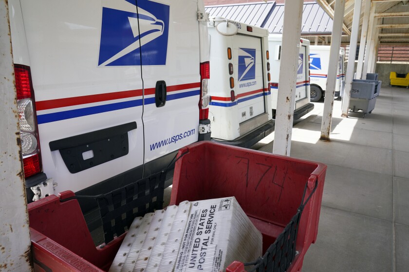 Mail delivery vehicles are parked outside a post office.
