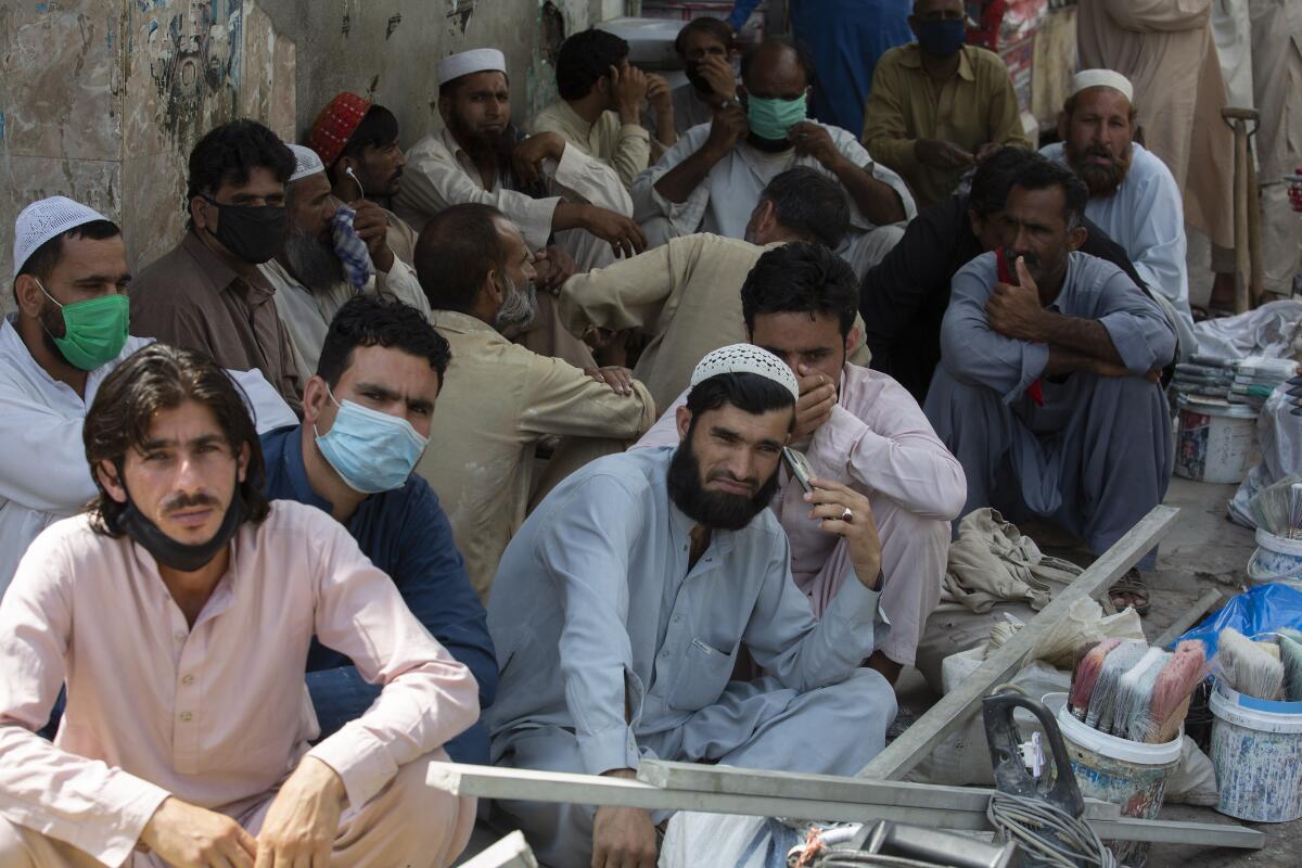 Unmasked laborers wait to be hired by customers in Rawalpindi, Pakistan, earlier this month.