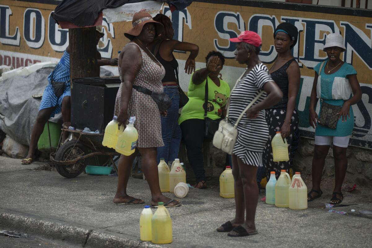 Women being photographed selling contraband gasoline in plastic gallons jugs on a street in Port-au-Prince, Haiti.