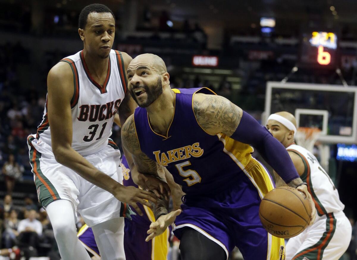 Carlos Boozer is fouled as he drives past Bucks center John Henson during the first half of the Lakers' 113-105 overtime loss Wednesday in Milwaukee.